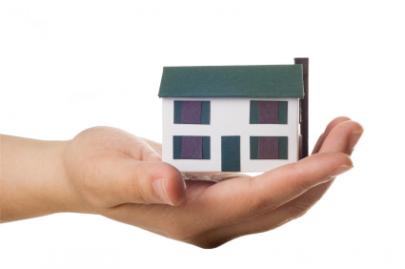 A hand holding a small house